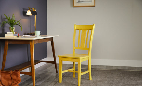 Chair stained in yellow, in front of desk.