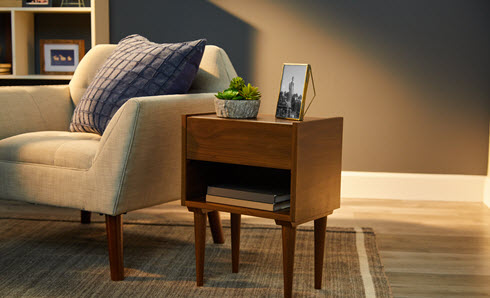 Stained side table next to sofa, in living room painted in olive-taupe.