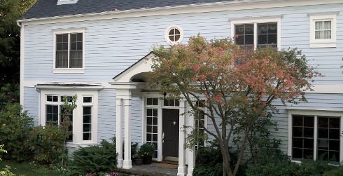Colonial house with light blue walls, white trim, and black door.