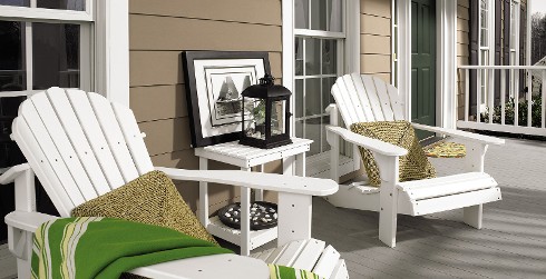 Beach outdoor porch with brown walls, white trim, white beach chairs, and green door.