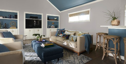 Casual living room with light gray on walls, blue on ceiling, white on trim and cabinets, and light tan upholstered chairs and couch