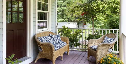 Wicker loveseat and chair on a wooden porch.