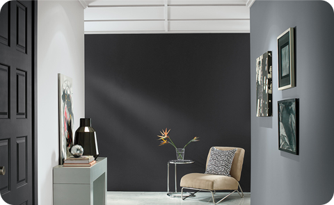 Grey room with dark wall, chair, frames on the wall.