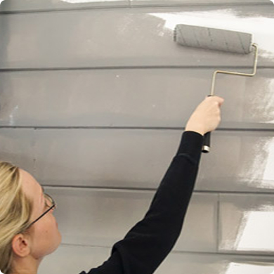 A women painting a wall with a roller