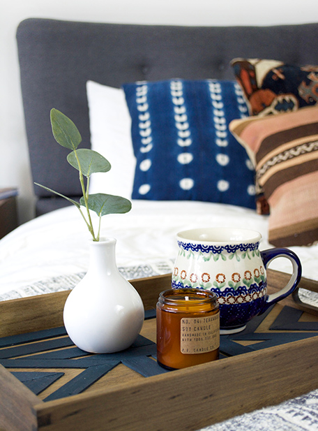 Finished serving tray on a bed, holding a vase and candle