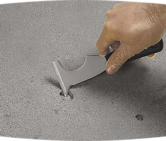 Person holding a tool repairing a hole in concrete
