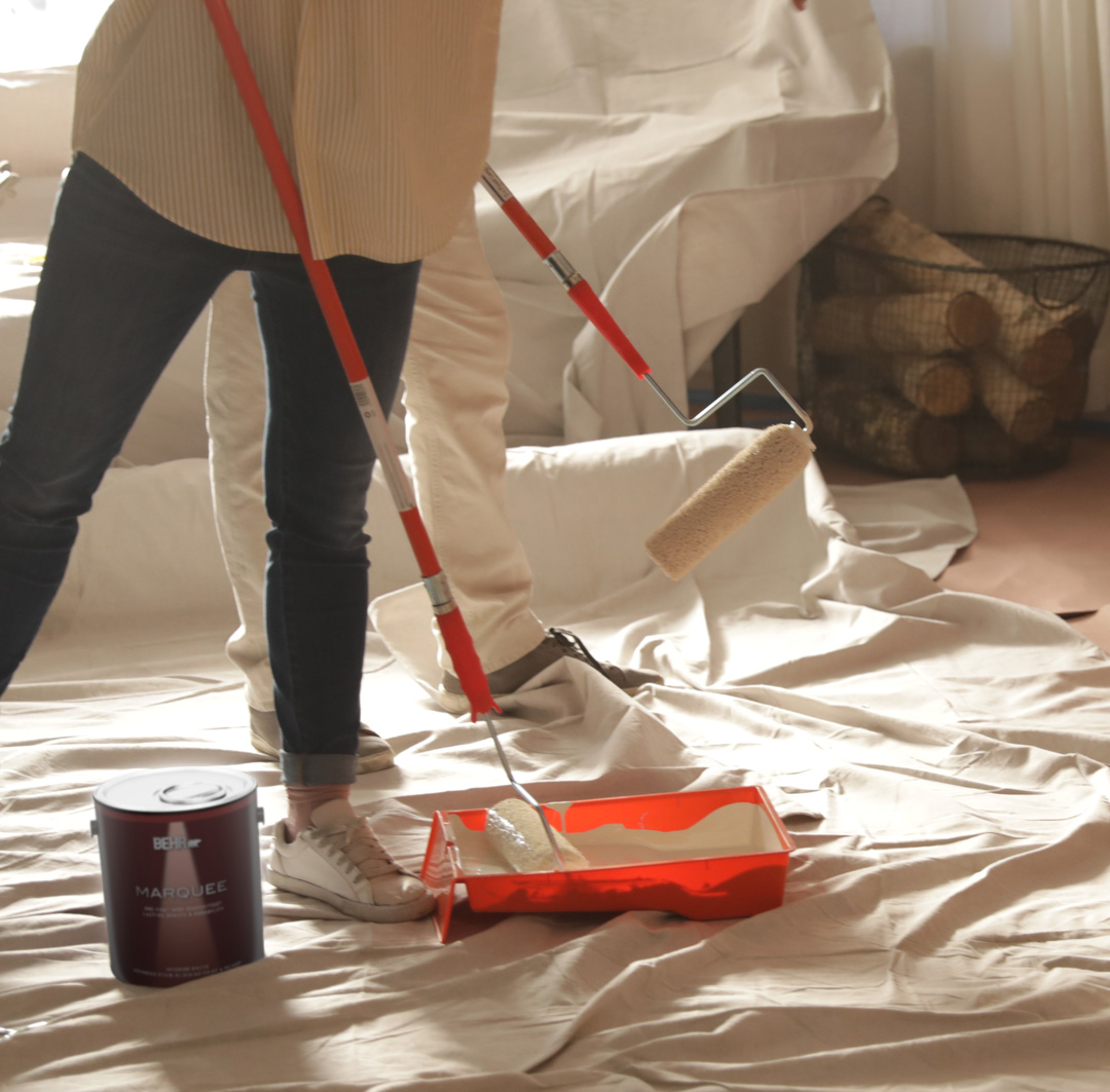 Smaller image of people painting with paint rollers and drop clothes