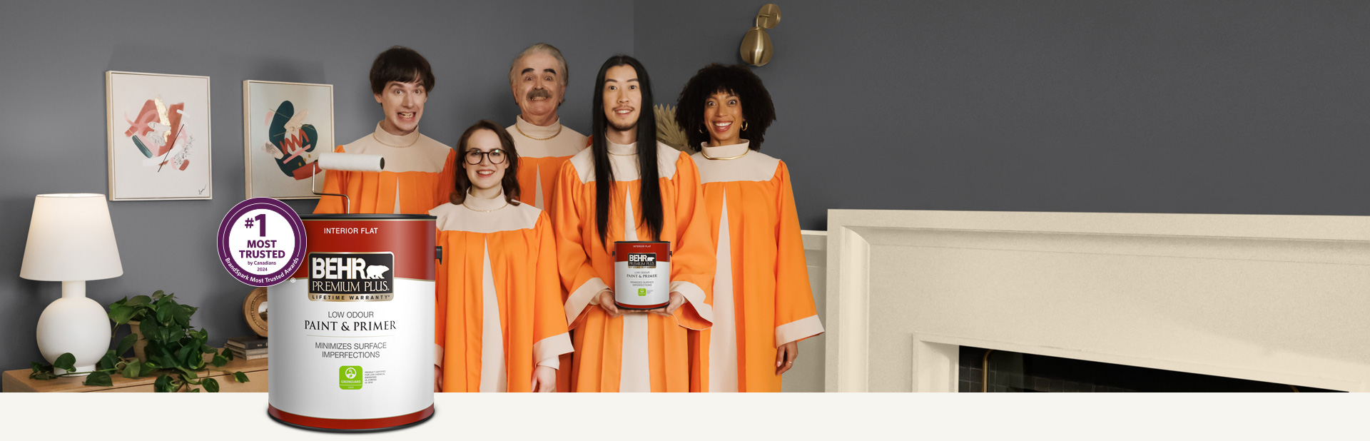 Choir standing in a painted living room and holding a can of Behr Premium Plus Interior Flat Paint