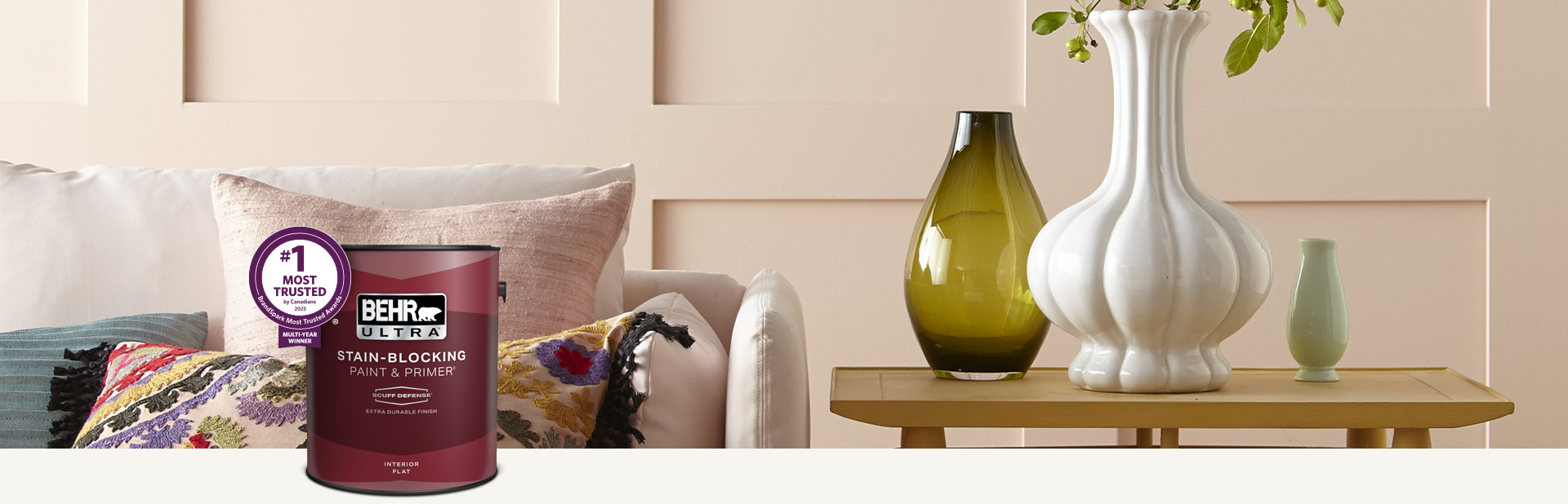 Living room with a pale peach colored wall and a can of Behr Ultra Scuff Defense Interior Paint in the foreground