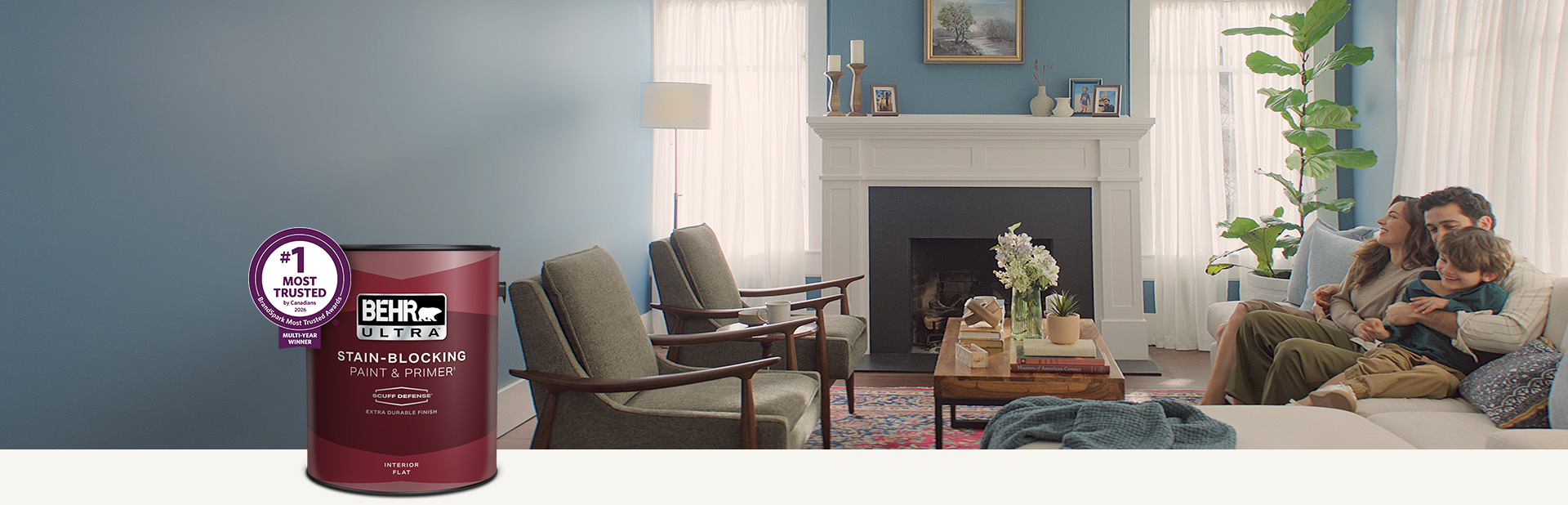Living room with a pale peach colored wall and a can of Behr Ultra Scuff Defense Interior Paint in the foreground