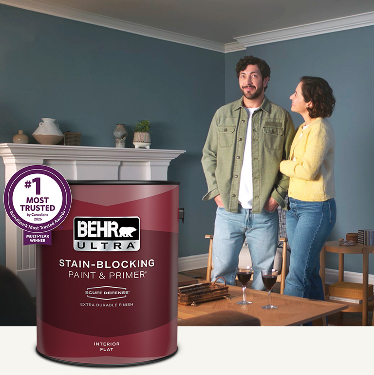 Living room with a pale peach colored wall and a can of Behr Ultra Scuff Defense Interior Paint in the foreground mobile image.