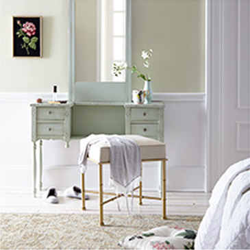 Makeup table with mirror and chair with flower picture hanging on the wall