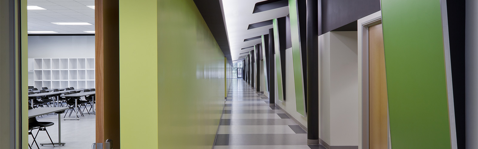 An image of a large empty classroom hallway with a green, grey and white colour combination.