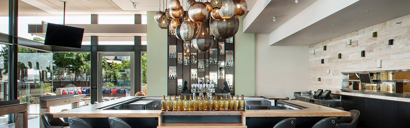 Image of an empty modern bar. In the middle of a bar there are Moroccan lamps hanging from the ceiling and you can see the outside from the inside of the bar