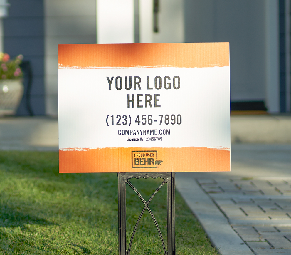 A close up view of a yard sign that is displayed on a front lawn. The Yard sign is printed with the words YOUR LOGO HERE - (123) 456-7890 - company.com - PROUD USER BEHR.
