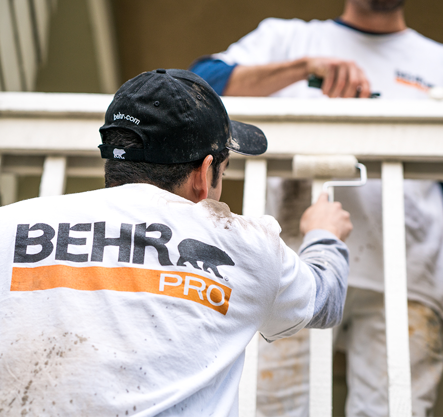 Mobile view of a pro painter spray painting the exterior wall of a house.