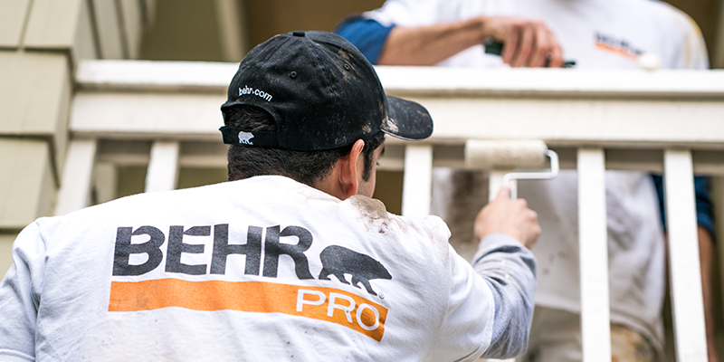 Desktop view of a pro painter spray painting the exterior wall of a house.