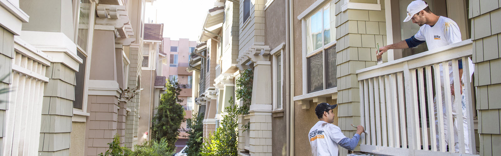 Large image of 2 Pro painters painting the wooden railings of the exterior of an apartment block.