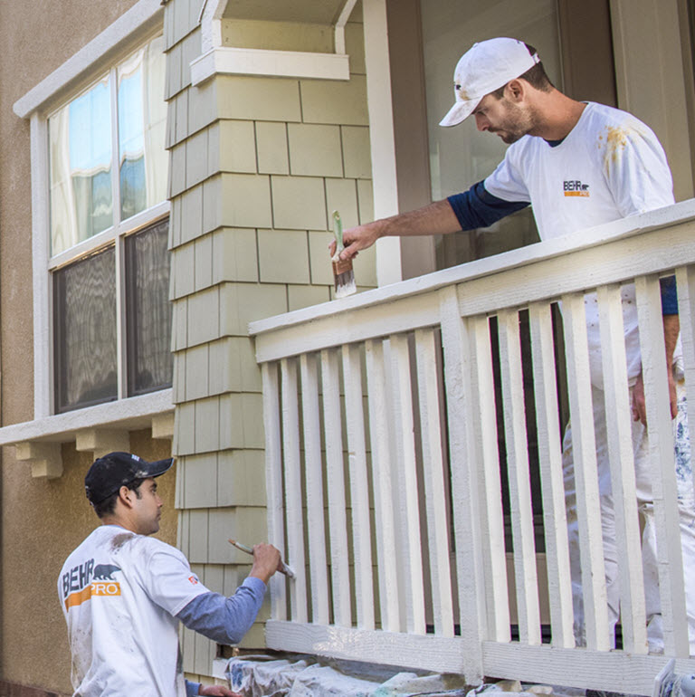 Small image of 2 Pro painters painting the wooden railings of the exterior of an apartment block