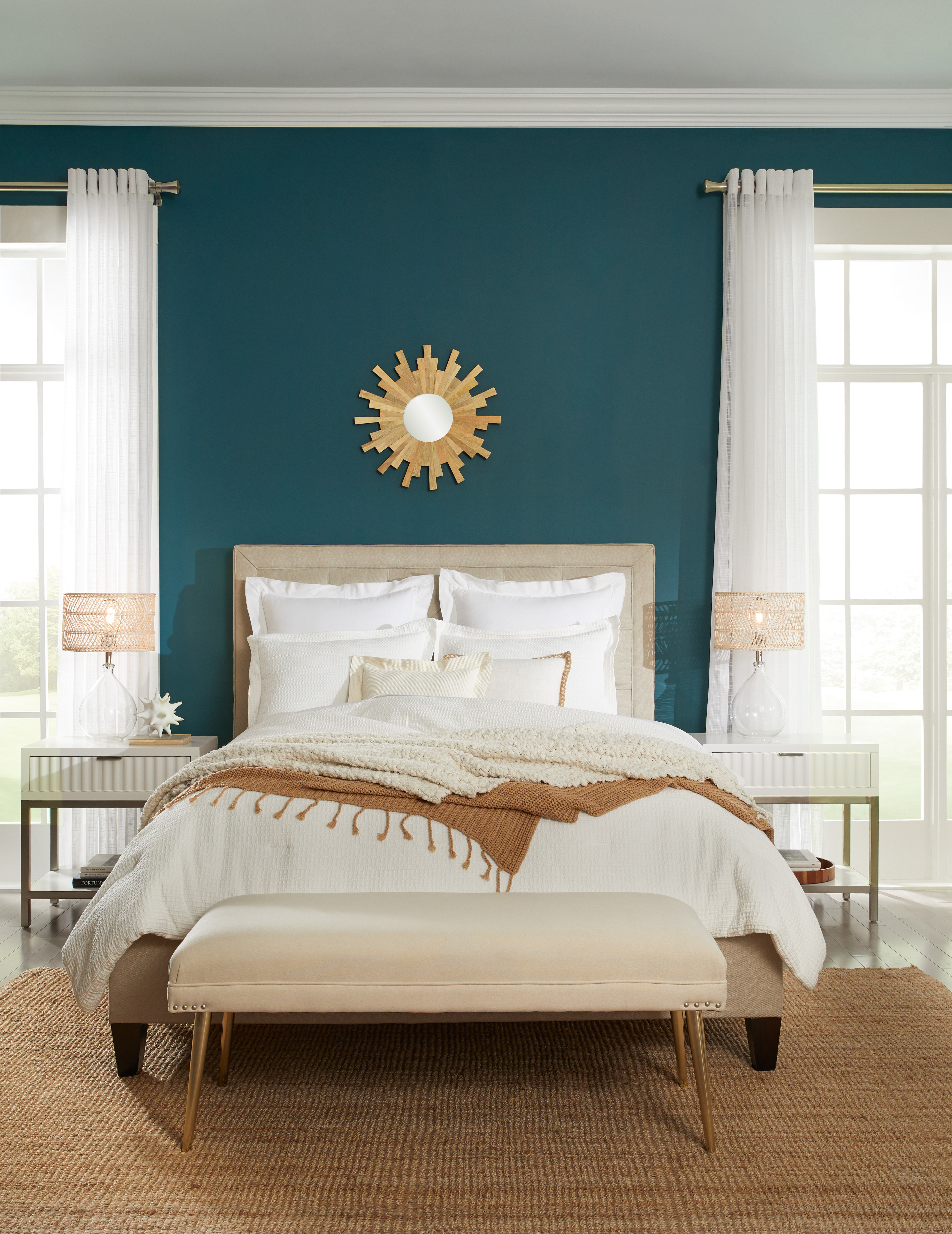 A bedroom with dark  teal color walls and white trim and ceiling, the color used on the wall is called Ocean Abyss. 
The bedroom is dresses in off white neutral bedding and a brown accent blanket.  