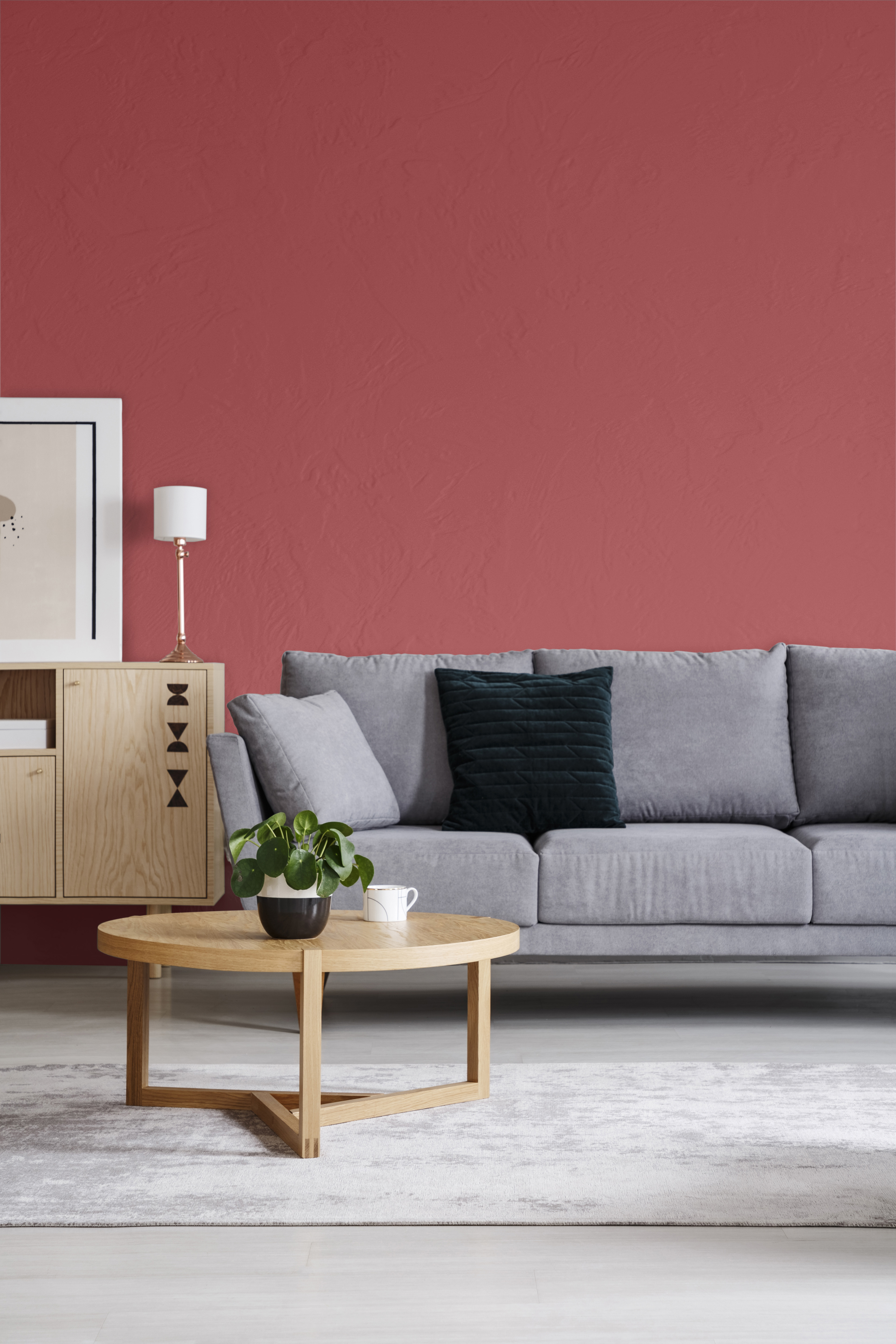 A red wall in an elegant living room interior with a sofa and round table, the color used on the wall is called Lingonberry Punch. 