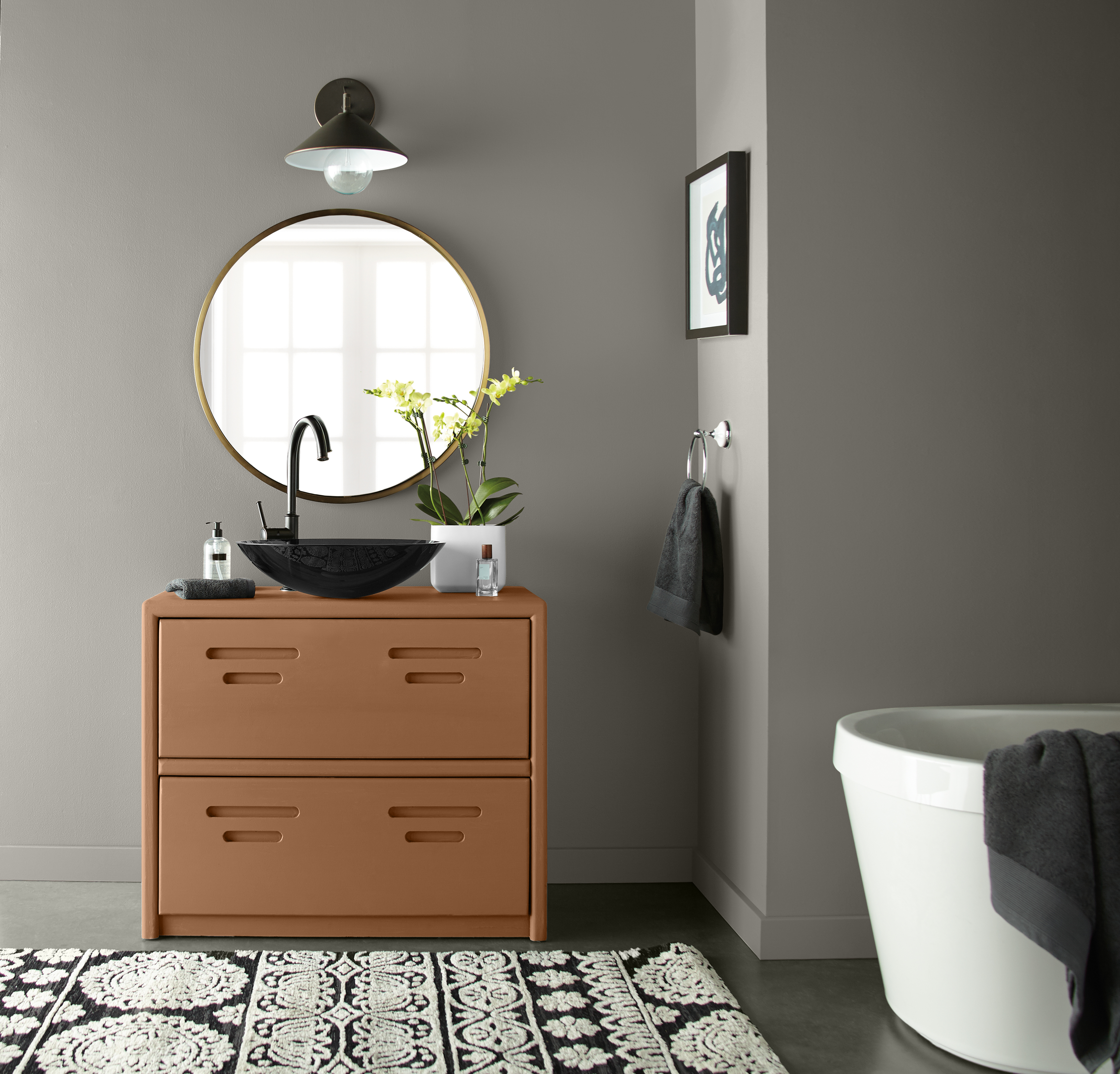 An eclectic gray bathroom with a round cotemporary  bath tub  and a unique and interesting vanity painted in an earthy orange color called Maple Glaze. 