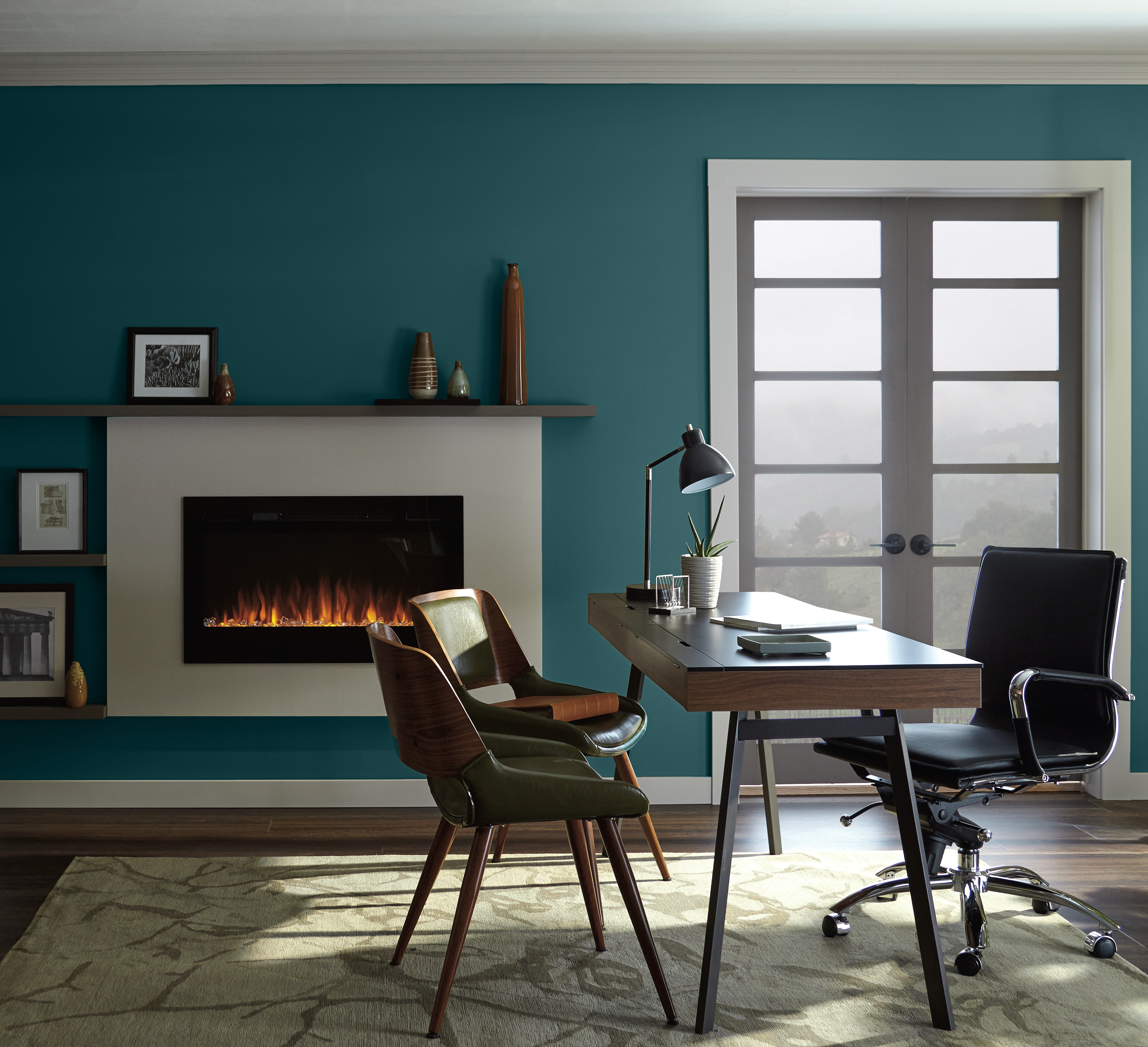 A contemporary office with a fireplace. the furniture used in the room has a retro feel too it.  There is also a double wood and glass door that allows you to see hazy green vista. 
