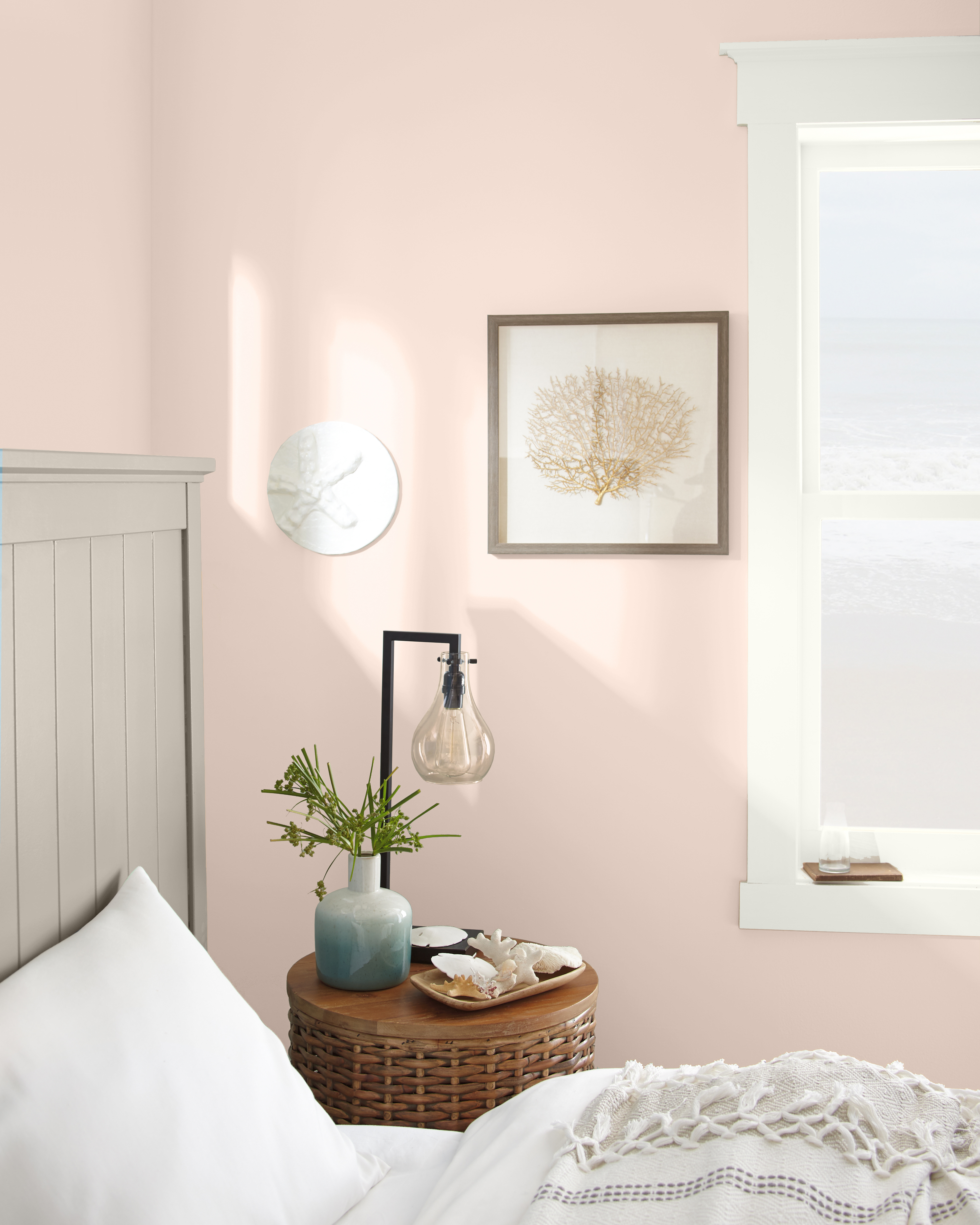 Coastal inspired bedroom image with walls in a light pink. Neutral tones are used throughout bedroom.