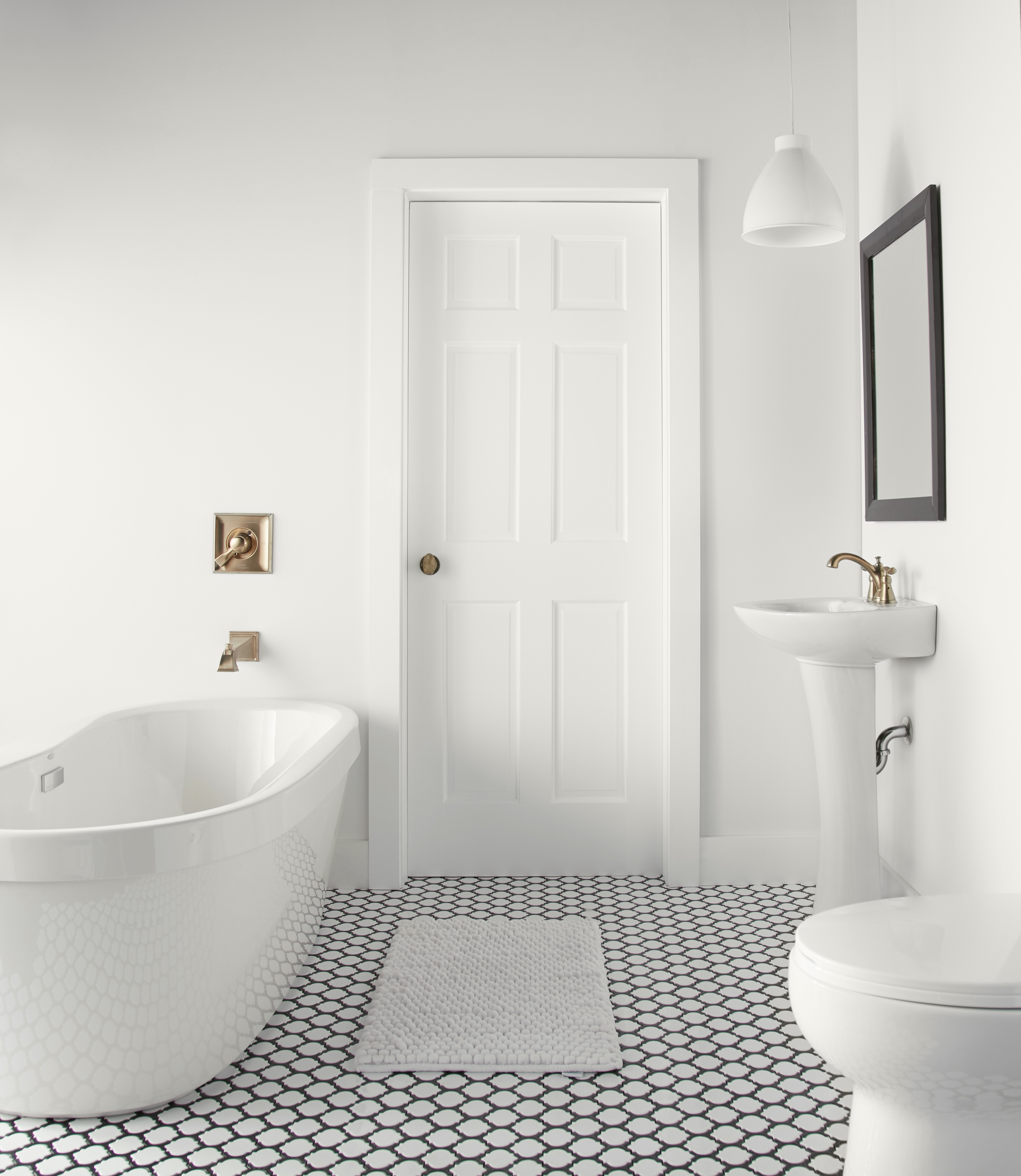 A modernized classic bathroom painted in all white paint.  The floor is black and white tile and the overall look of the room is clean and spacious.   