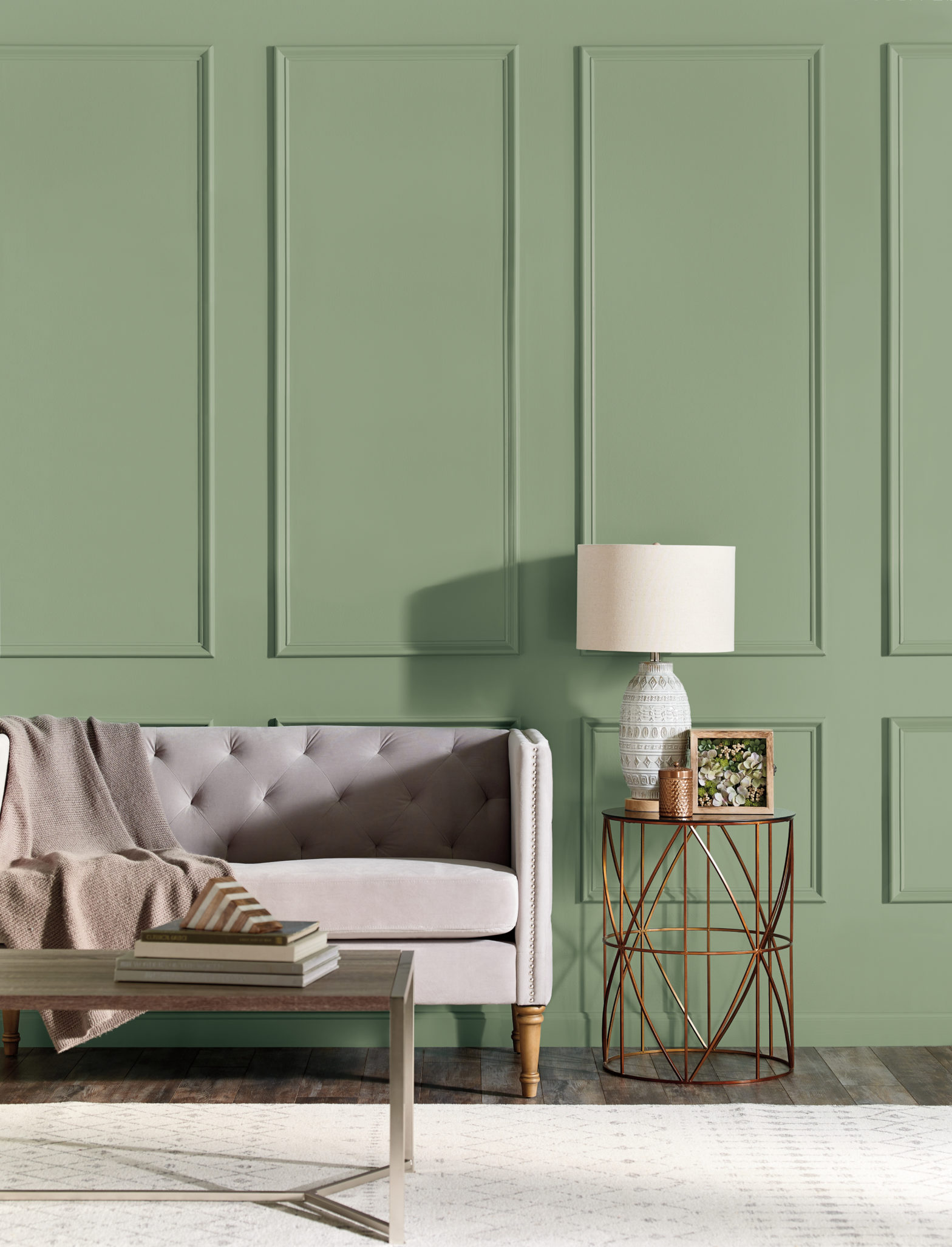 A stylish contemporary living room setting, there is an upholstered chic sofa and an accent side table in gold metallic finish. The color on the wall is called Laurel Tree. 