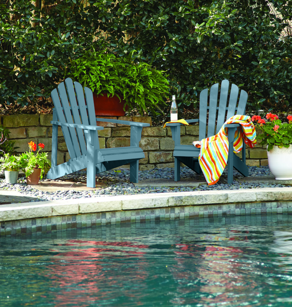 An edge of a pool with two chairs placed next to it, they are painted in a muted blue hue.