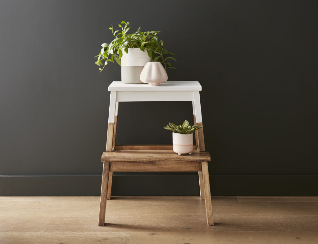 A wood step stool with the top part painted white. Flowers are placed on the steps of the stool.