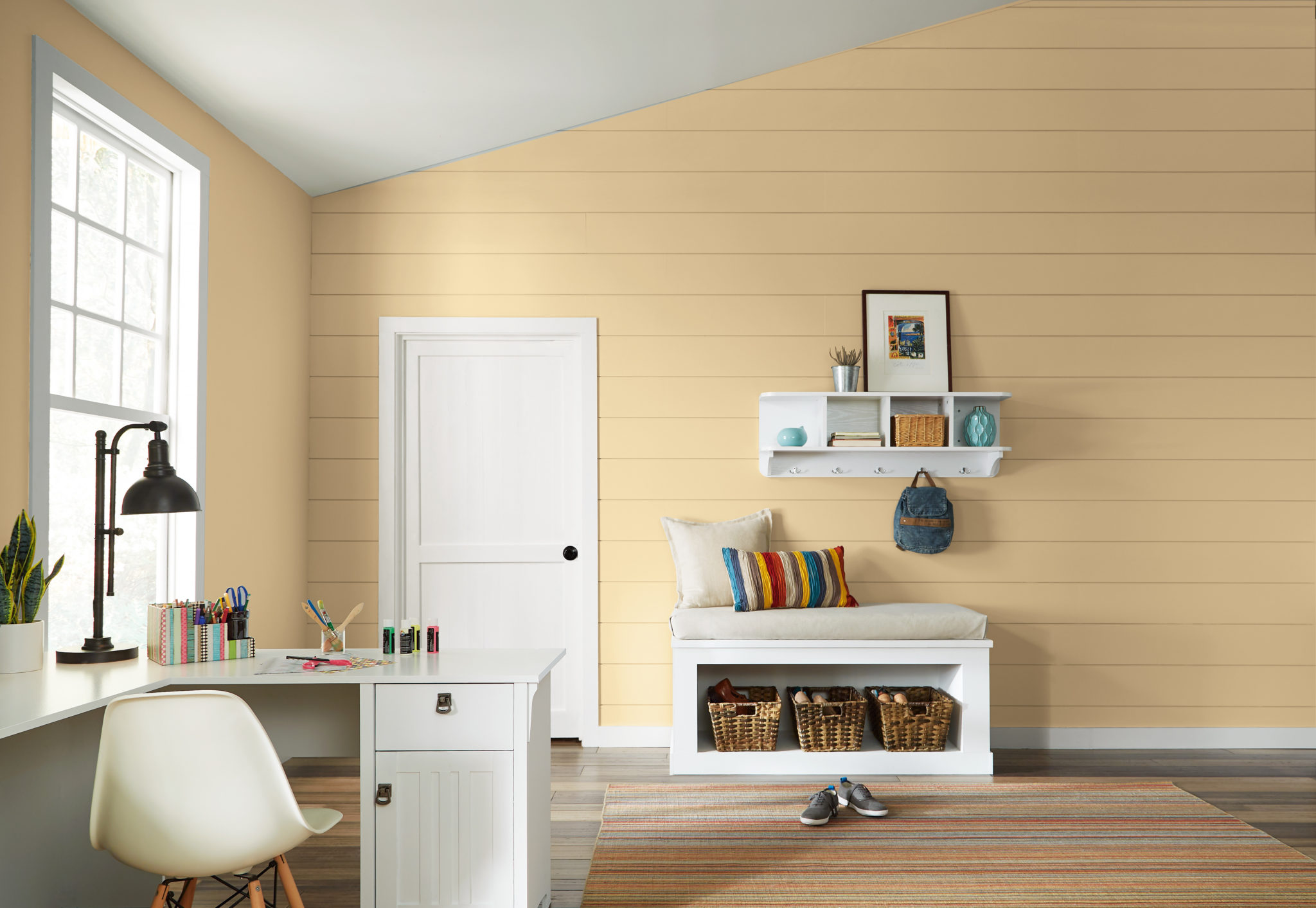 A playroom-office painted in a wholesome and welcoming yellow called Corn Stalk.  The room features are hardwood floor and it is decorated with colorful elements. 