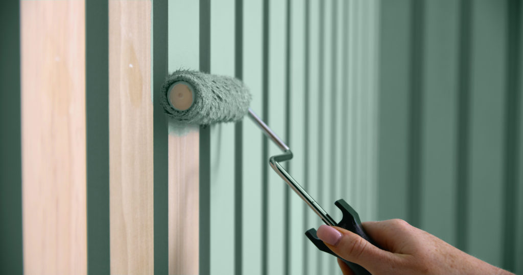 A person painting the wood slats with a roller.