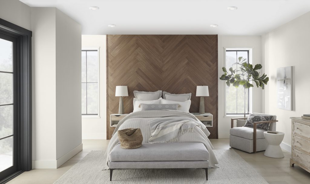 A stylish bedroom painted in a serene and balanced white. The soft hues used throughout the space beautifully contrast the wooden wall feature.