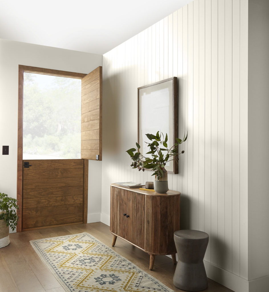 A modern farmhouse home entry, the vertical planked walls in this open, sunny room were painted white to create an airy and welcoming ambiance. 