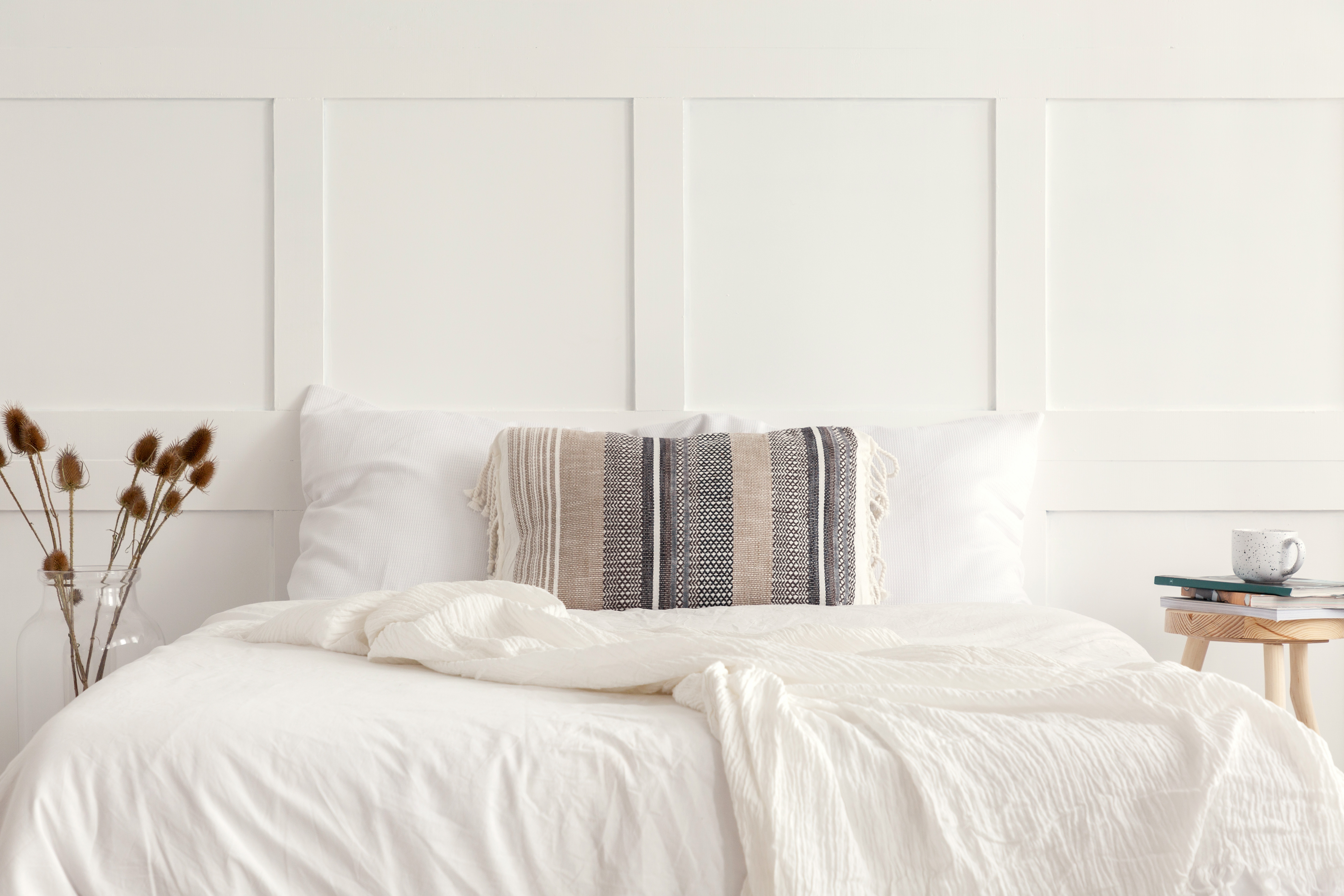 An elegant white bedroom with simple details on the walls.