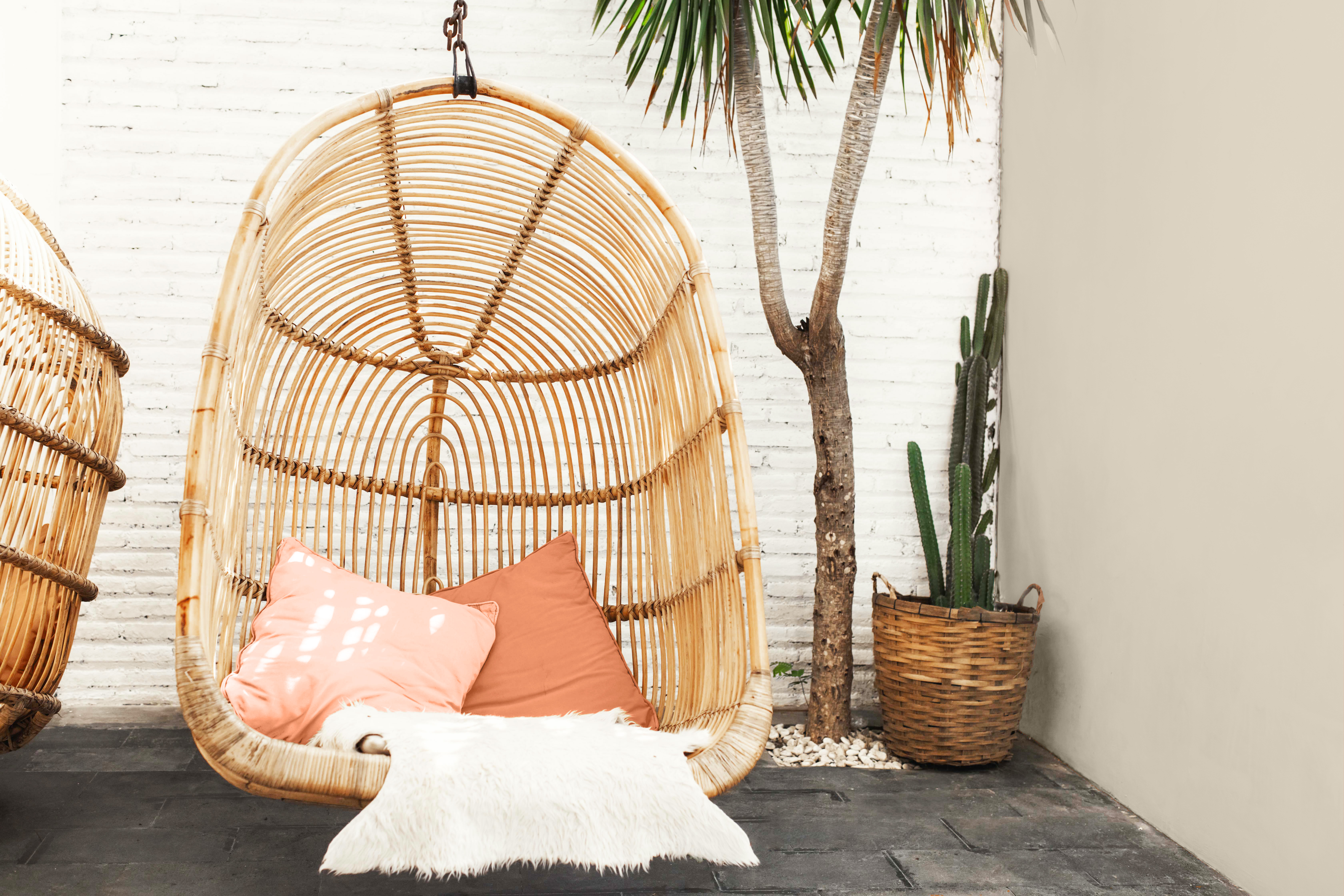 A small outdoor space decorated with boho outdoor elements and a bamboo swing, with one wall painted in Even Better Beige.