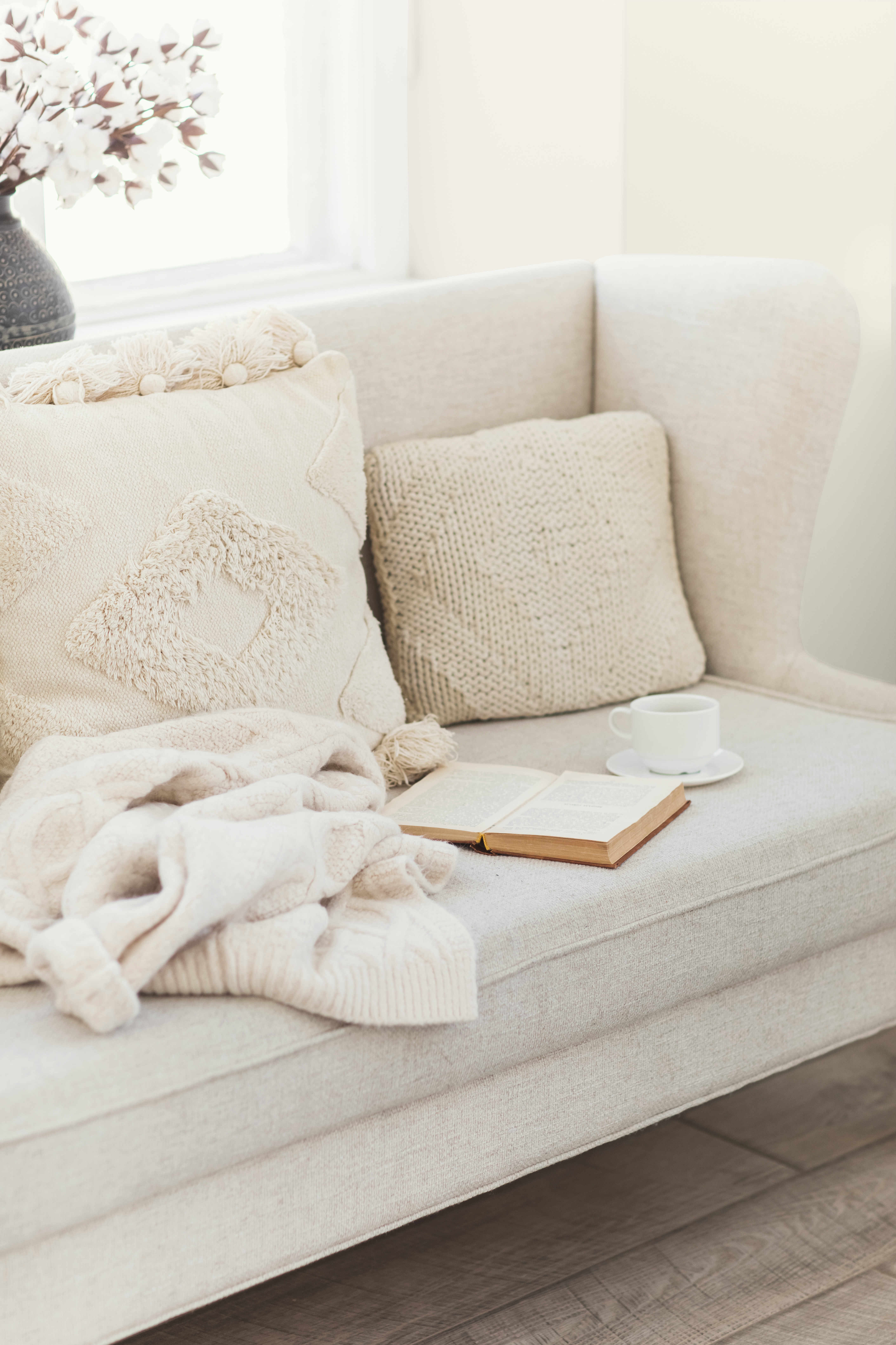 A cozy living room painted in the colour Blank Canvas with a beige sofa and knitted accessories.