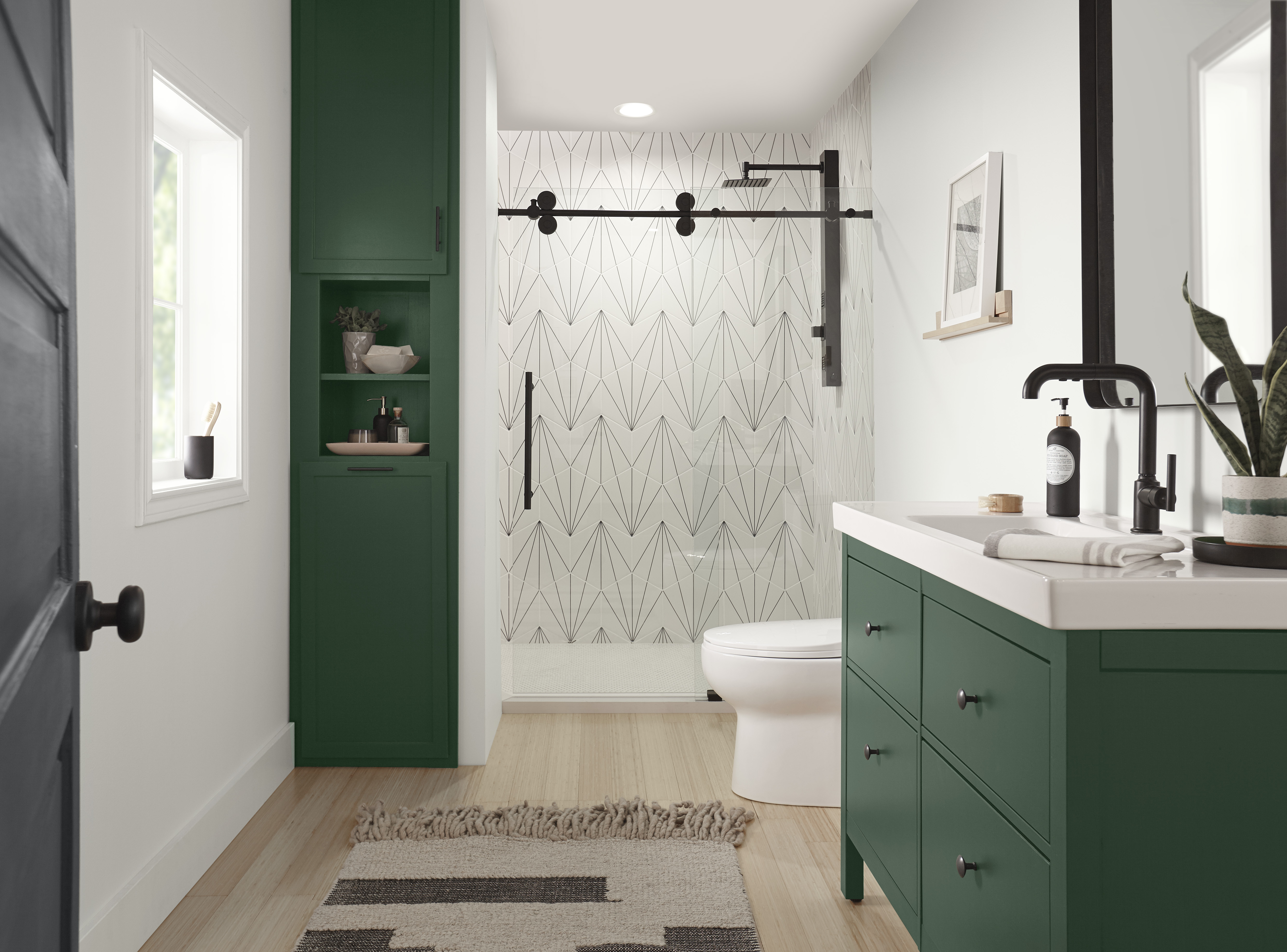 A modern bathroom with cabinets painted in a deep green colour and matte black hardware. 