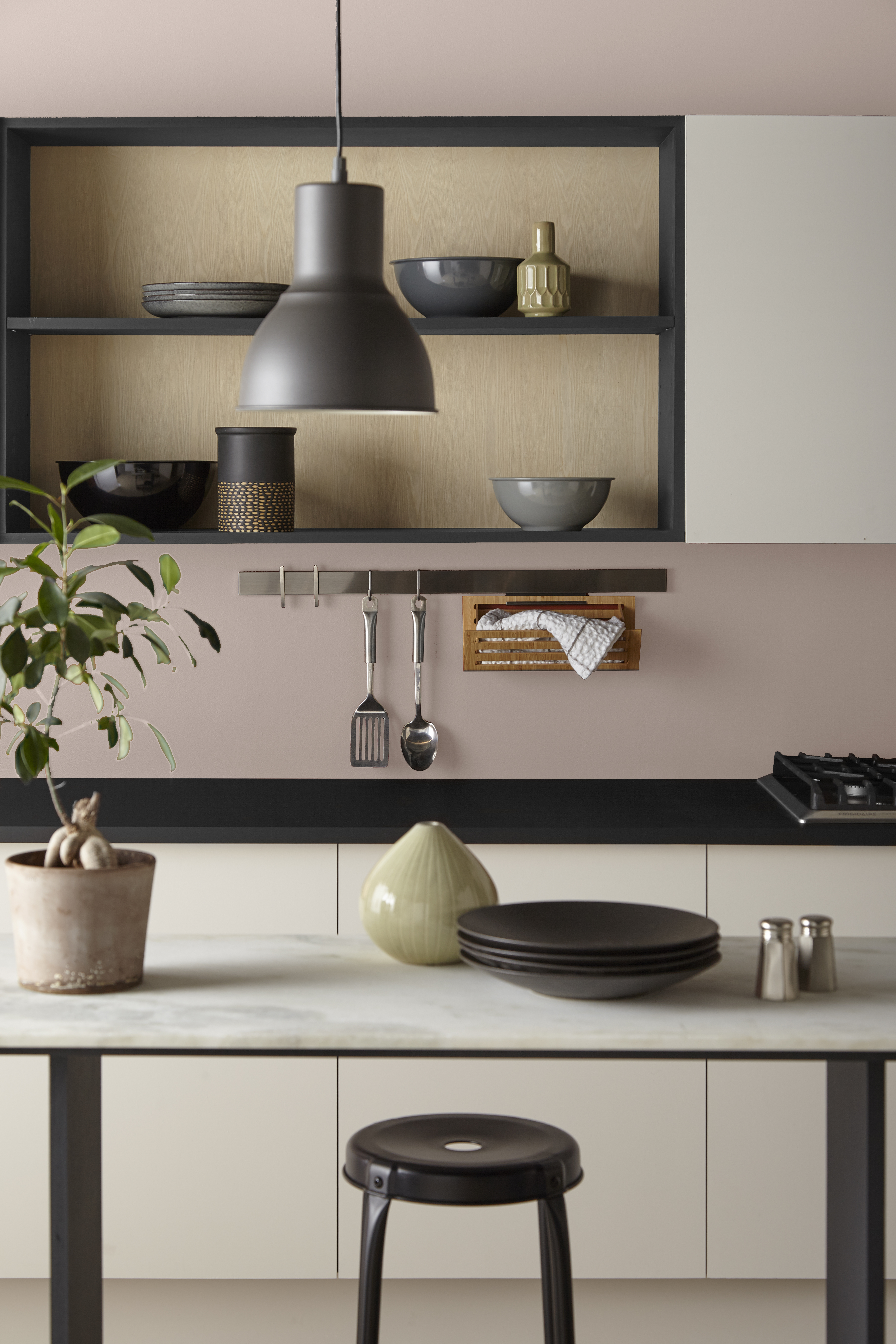 A modern kitchen with walls painted in Smokey Pink and contrasting white and black cabinets and trim
