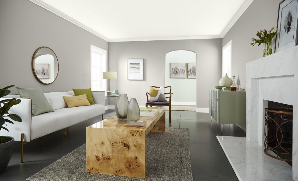 A large living room that has a view into the hallway, with walls painted in a warm greige colour