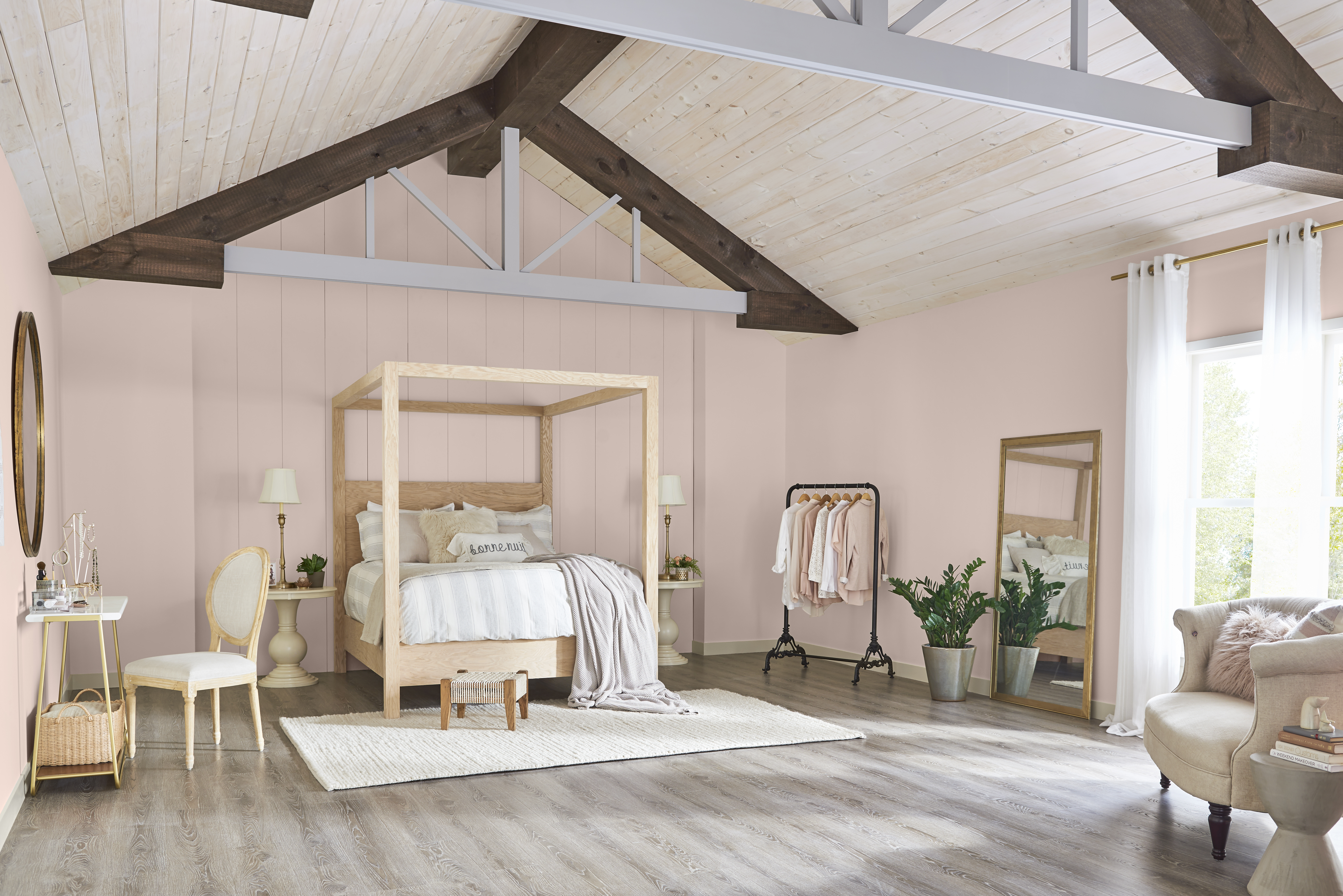 A bedroom with walls painted in Smokey Pink and a large wooden canopy bed styled with neutral pillows and bedding