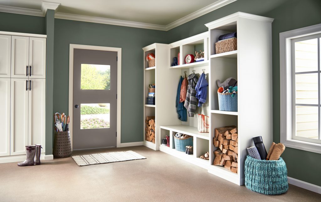 A spacious entryway with walls painted in Pinecone Hill, styled with tall white cabinets for storage