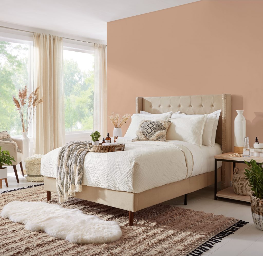 A bright bedroom with walls painted in a warm peach colour