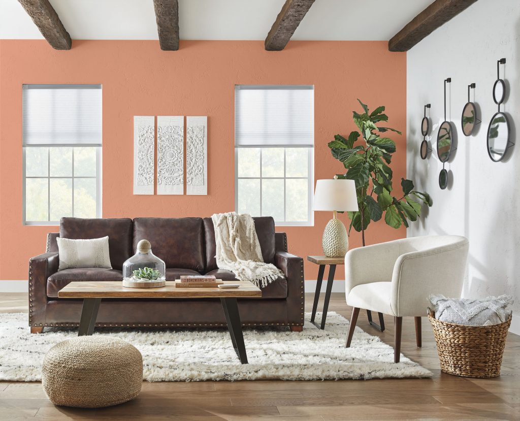 A living room with an accent wall painted in a bright peachy orange hue