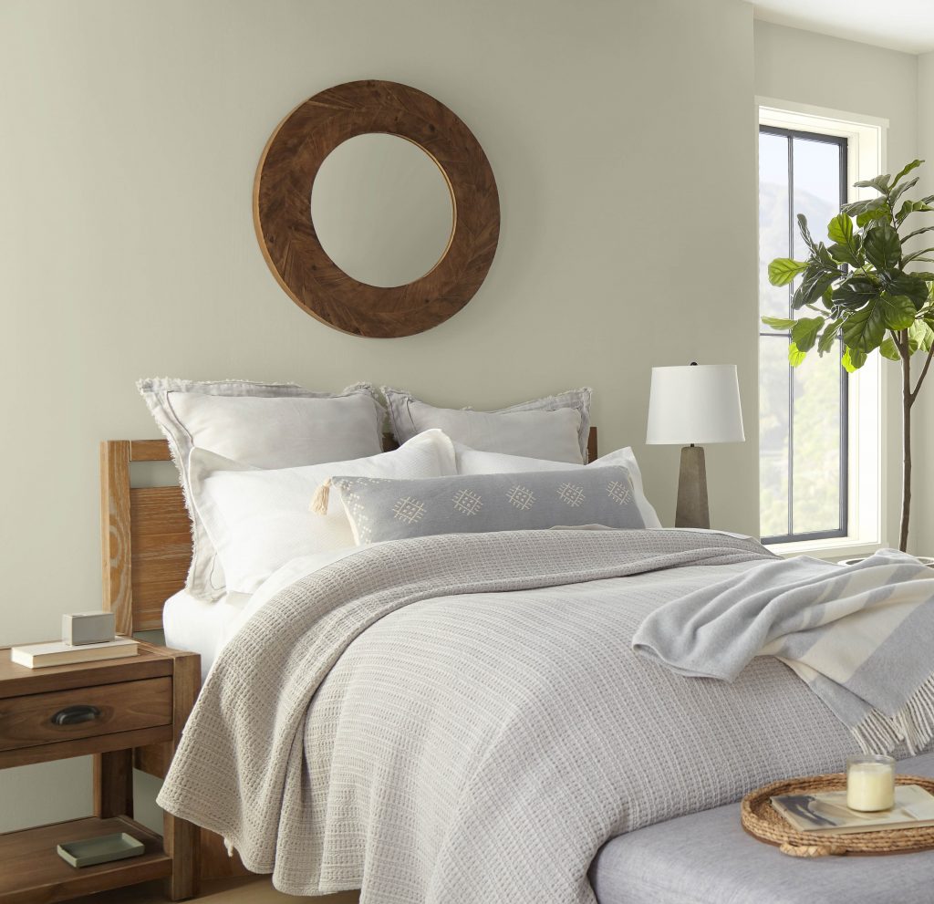 A bedroom with walls in the colour Jungle Camouflage and complementing neutral-coloured bedding and pillows