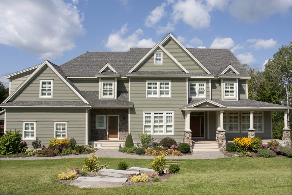 A large house exterior with siding in the colour Jungle Camouflage paired with white trim and a neutral roof