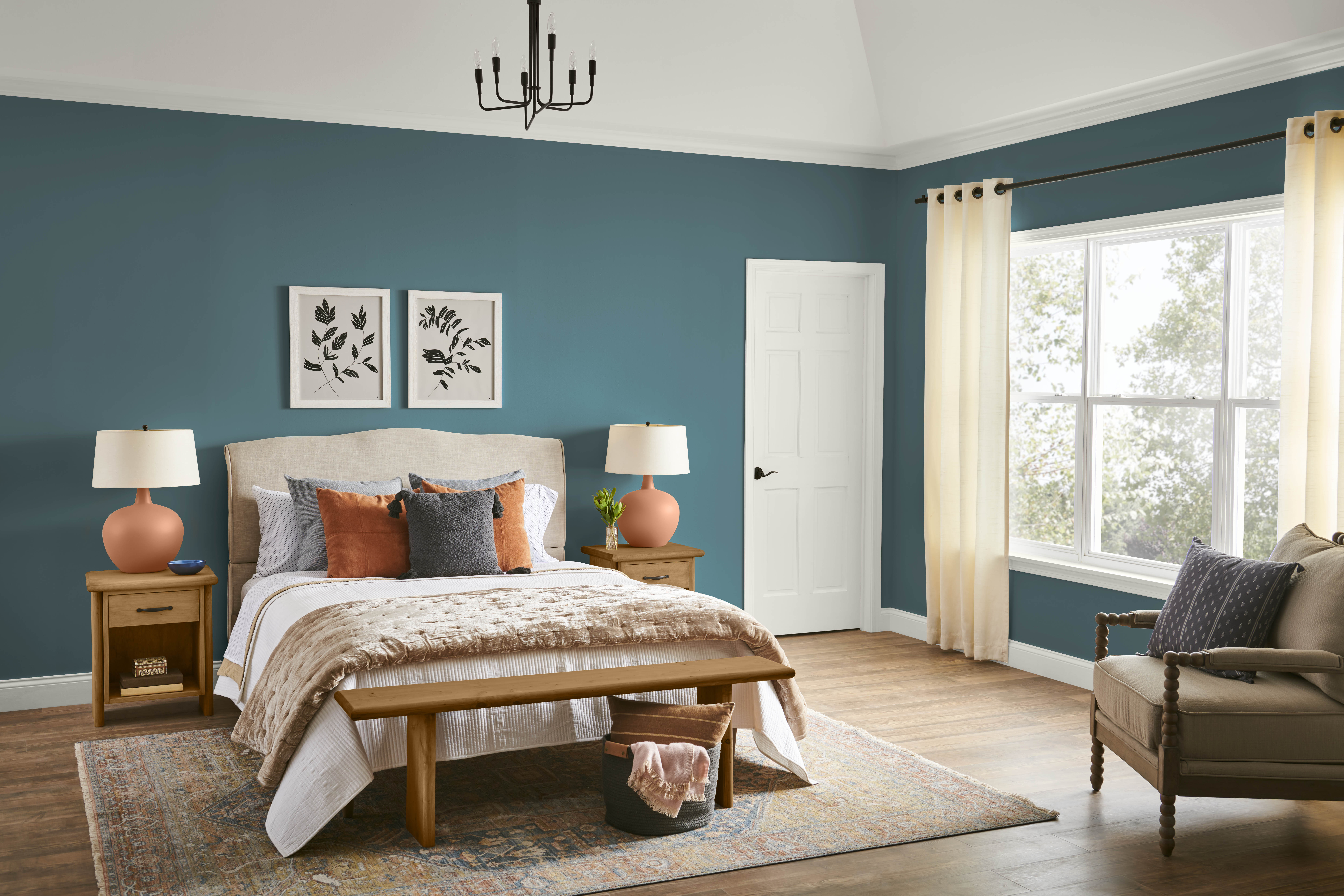A bedroom with walls in the colour Sophisticated Teal, styled with neutral and terra cotta furniture and accents 
