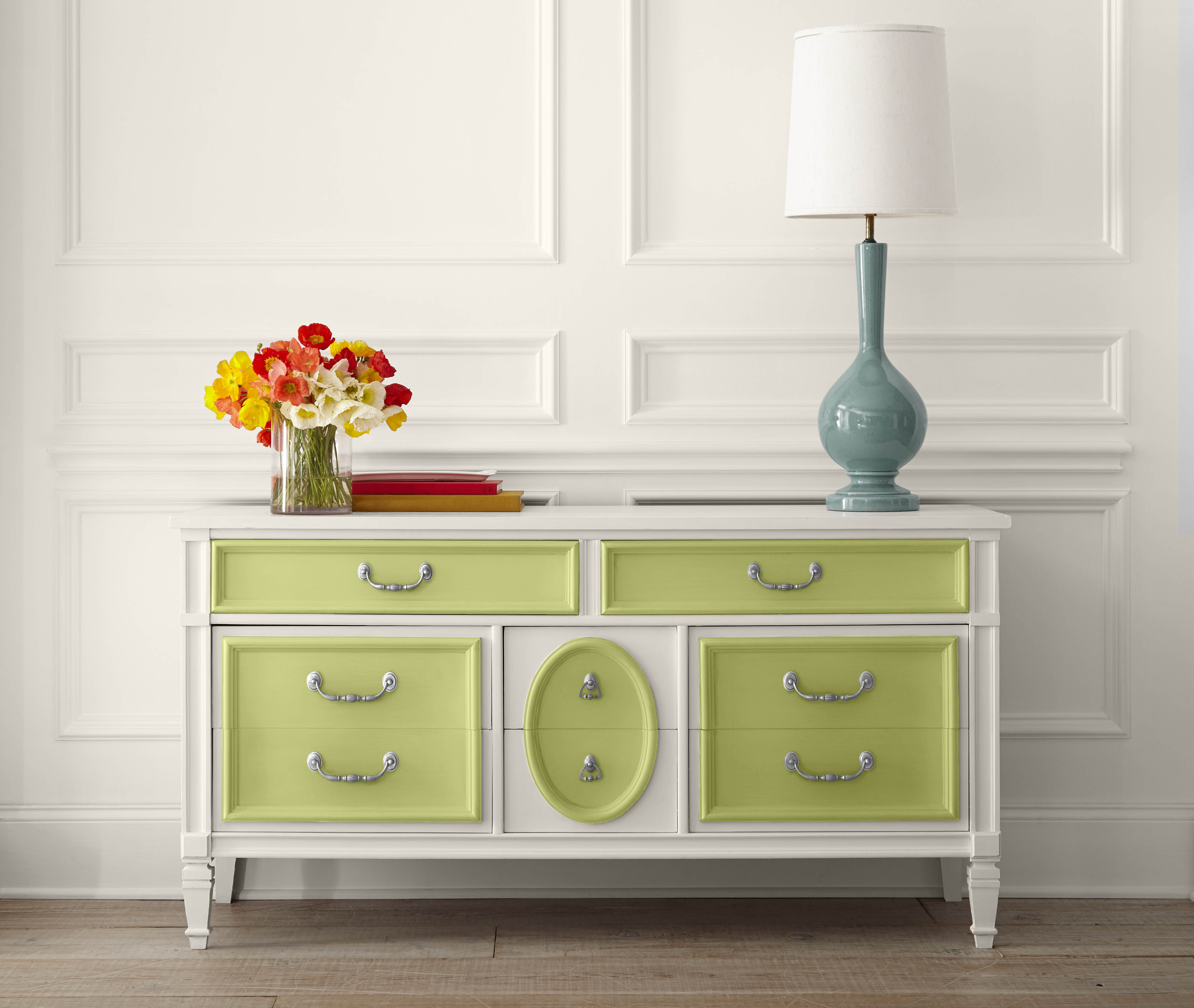 A white antique dresser with light green accents